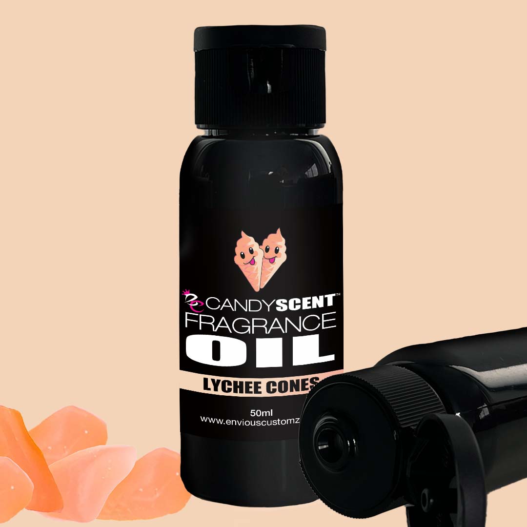 A black bottle labeled "CANDYSCENT™ Fragrance Oil" (50ml) with a cartoon image of two pink lychees. The bottle is standing upright, with one lying horizontally next to it, and four small pieces of lychee placed at the bottom left corner. Ideal for use in your oil burner.