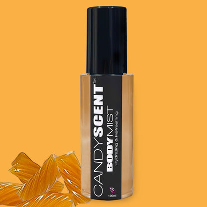 A 100ml bottle of CANDYSCENT™ Hydrating Body Mist with a black cap and label is displayed against an orange background. Text on the label reads "Hydrating & Refreshing." Pieces of caramel candy are placed beside the bottle, highlighting its nourishing ingredients like witch hazel.