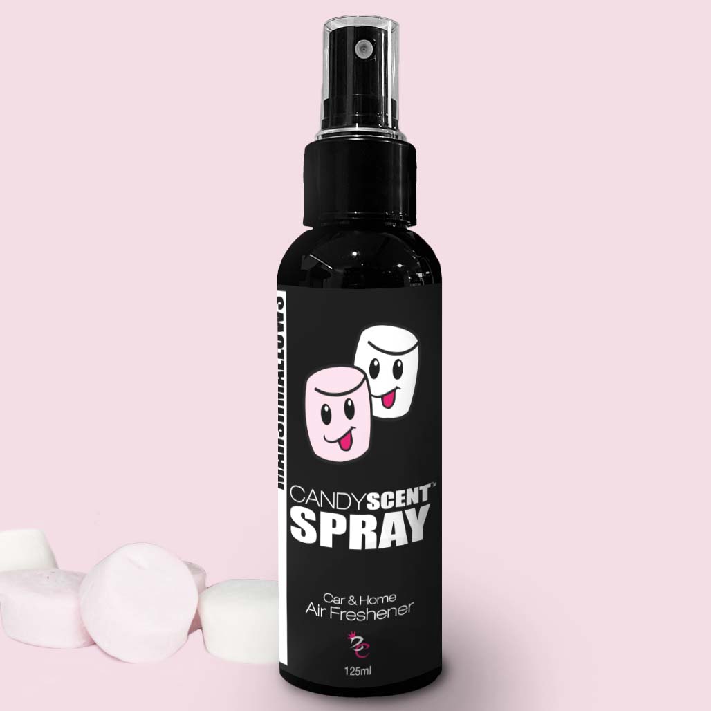 A black spray bottle labeled "Candy Scent Spray" featuring illustrations of two joyful marshmallows offers a long-lasting fragrance. It is identified as a CANDYSCENT™ Car & Home Scent Spray, 125ml in size. The bottle is set against a light pink background with real marshmallows nearby.