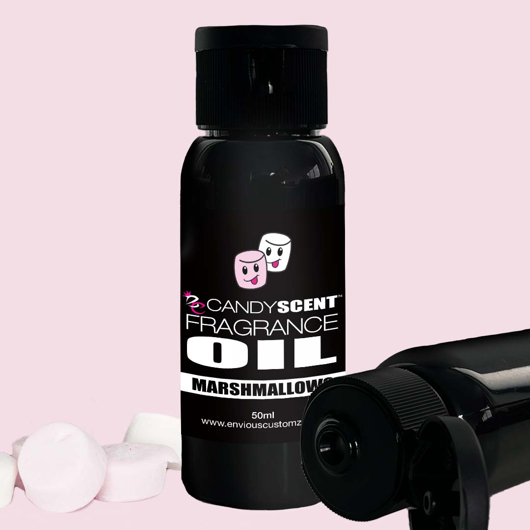 A black 50ml bottle labeled "CANDYSCENT™ Fragrance Oil" with a cute illustration of two smiling marshmallows on the front and "Marshmallow" written below. Two more black bottles and three pink marshmallows are positioned around the primary bottle against a light pink background, making it perfect for your oil burner.