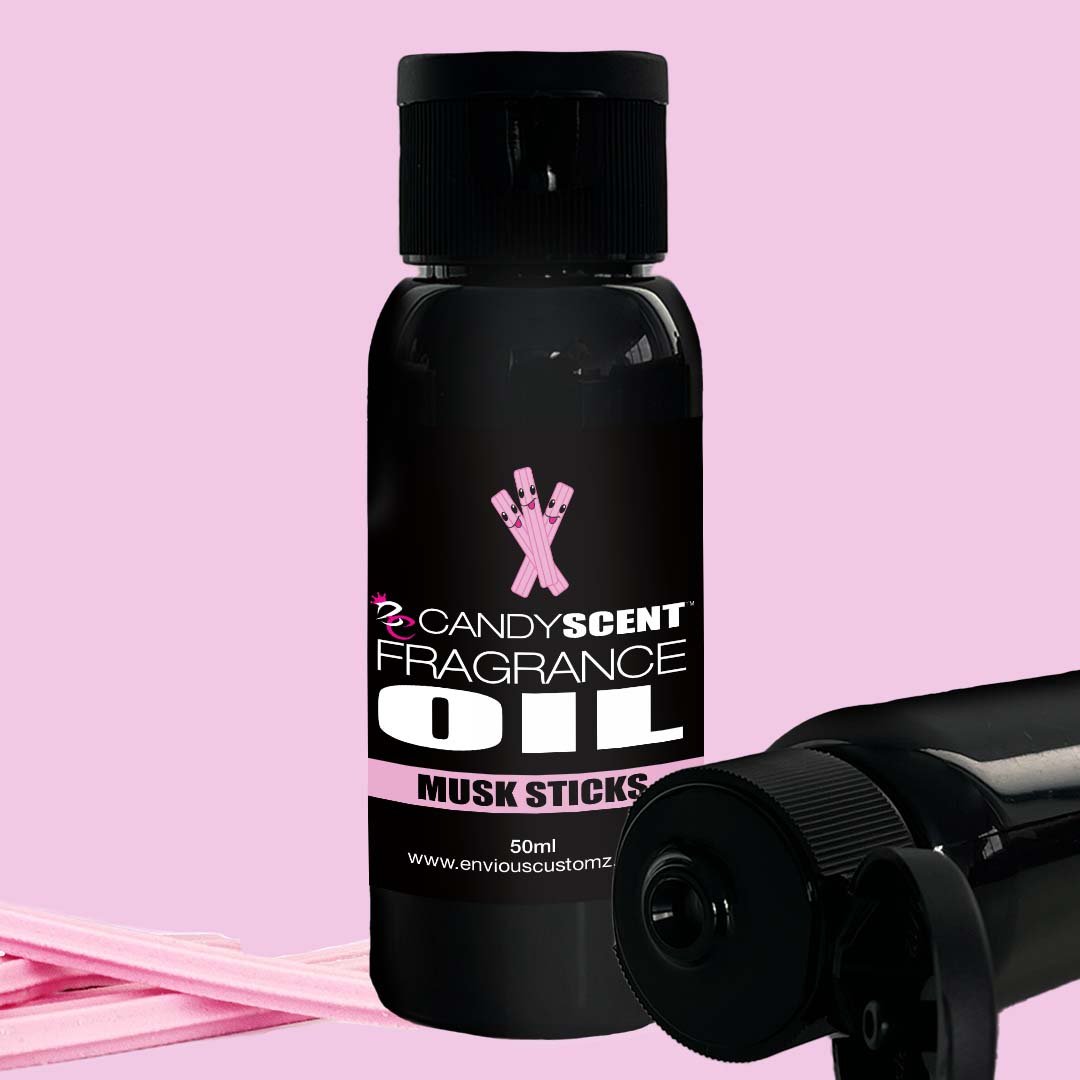 A black bottle labeled "CANDYSCENT™ Fragrance Oil - Musk Sticks 50ml" is displayed against a pink background. The bottle features a black cap and is accompanied by light pink sticks, perfect for your oil burner. Another CANDYSCENT™ Fragrance Oil bottle, similar in design, is partially visible. Ideal for your home scent collection.