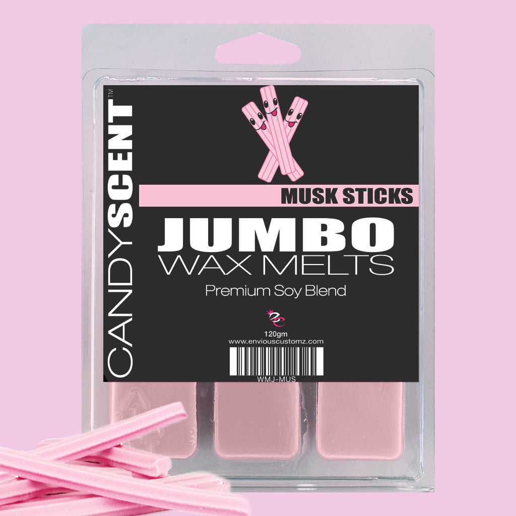 The packaging of CANDYSCENT™ Jumbo Wax Melts in the "Musk Sticks" scent showcases the pink, highly scented wax melts in a clear plastic container with detailed labels. Beside the packaging, a few pink wax sticks hint at the long-lasting aroma of CANDYSCENT™ Wax Melts.