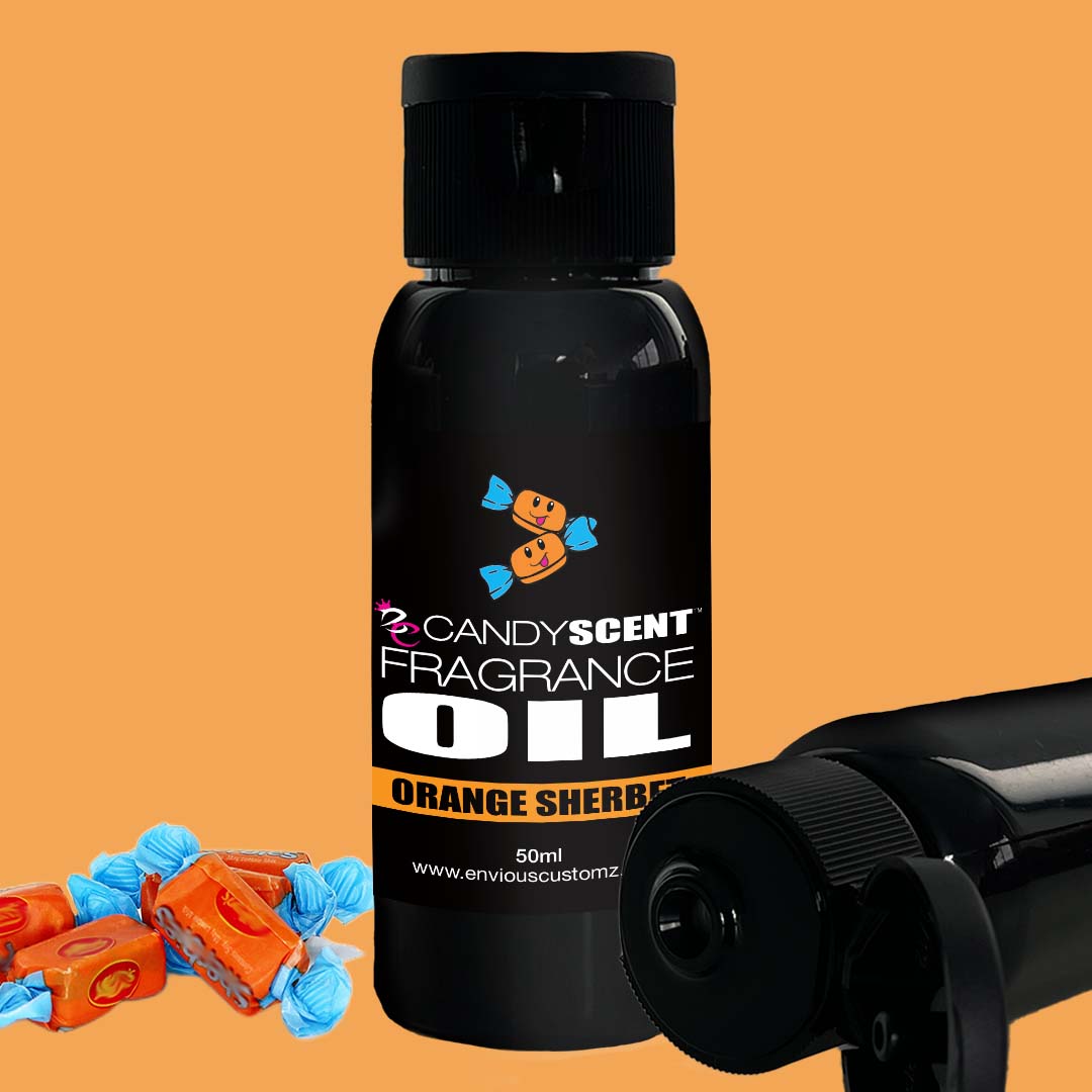 The image shows a 50 ml black bottle of CANDYSCENT™ Fragrance Oil in the Orange Sherbet scent variant, ideal for use in an oil burner. Four candies wrapped in orange and blue are placed next to it, with a second bottle partially visible in the background.