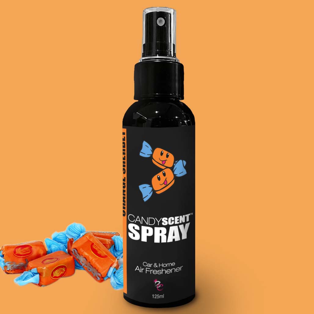 A 125ml black spray bottle branded as "CANDYSCENT™ Car & Home Scent Sprays" for air freshening, adorned with an image of two smiling wrapped candies on the label. This bottle provides a long-lasting fragrance. Nearby, several unwrapped orange candies with blue wrappers add to its delightful vibe.