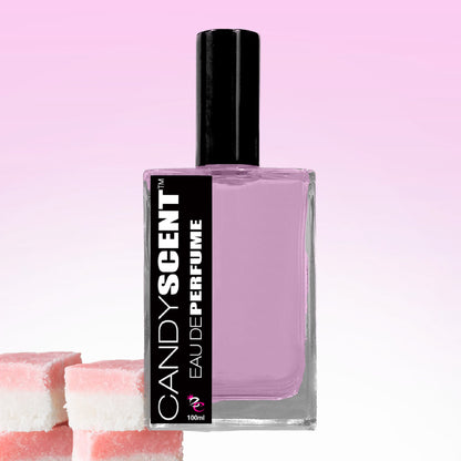 A clear perfume bottle with a black cap labeled "Eau De Perfume / Cologne" by CANDYSCENT™ sits against a pink gradient background. The bottle contains a light purple liquid, perfect for everyday wear. To the left of the bottle, two pieces of pink and white layered candy embody the sweet fragrances.