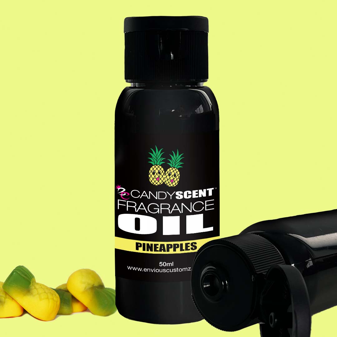 A 50ml black bottle labeled "CANDYSCENT™ Fragrance Oil - PINEAPPLES," adorned with pineapple imagery, sits beside two identical bottles and small yellow pineapple-shaped pieces against a vibrant yellow backdrop. Ideal for use in an oil burner or to enhance home scent.