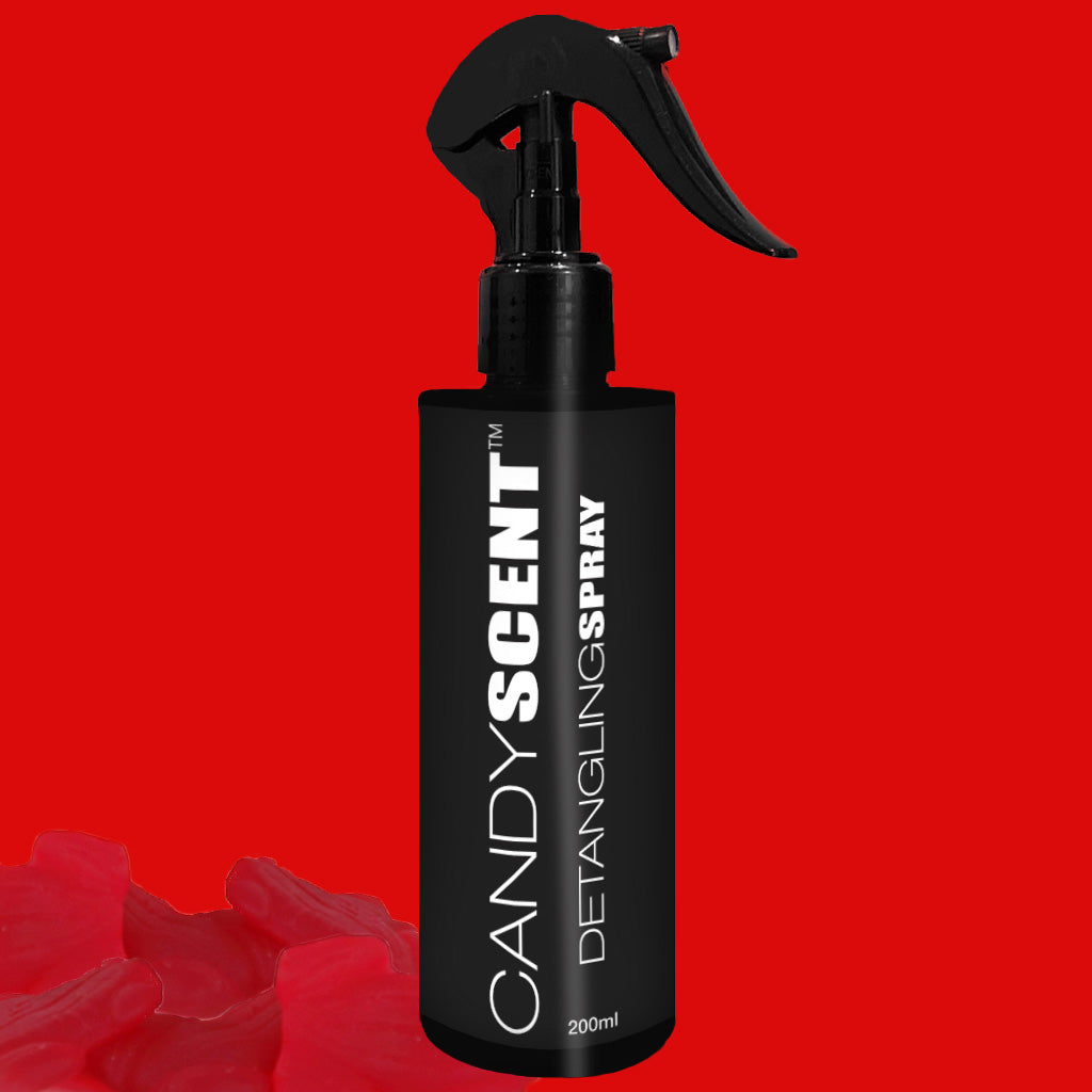 A 200ml bottle of CANDYSCENT™ Hair Detangling Spray, enriched with Jojoba Oil and featuring a spray nozzle, is displayed against a red background. The black bottle is adorned with several red, petal-like shapes at the bottom left corner of the image.