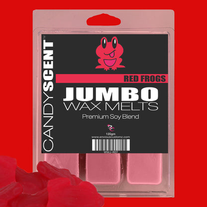 The image displays a package of Jumbo Wax Melts by CANDYSCENT™, adorned with a pink frog illustration on the front and containing five intensely fragrant wax squares. In the lower-left corner, there is a small pile of red frog-shaped CANDYSCENT™ Wax Melts, guaranteeing a long-lasting aroma.