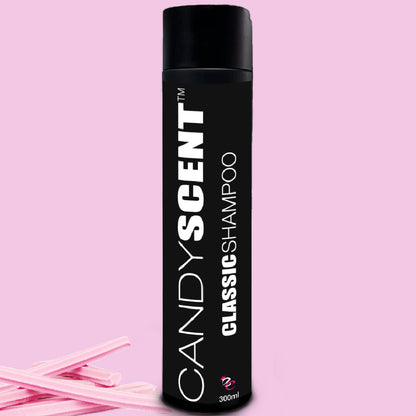 A black bottle of CANDYSCENT™ Classic Shampoo with white text stands upright against a pink background. This luxurious 300ml shampoo epitomizes premium hair care. Two pieces of candy are placed at the base of the bottle for a sweet touch.