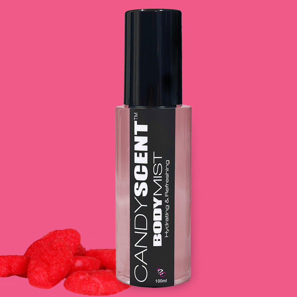 A 100ml bottle of CANDYSCENT™ Hydrating Body Mist with a black cap and label, set against a pink background. The label reads "Hydrating & Refreshing." Infused with witch hazel, this mist is perfect for your skin. Red gummy candies are scattered at the base of the bottle.