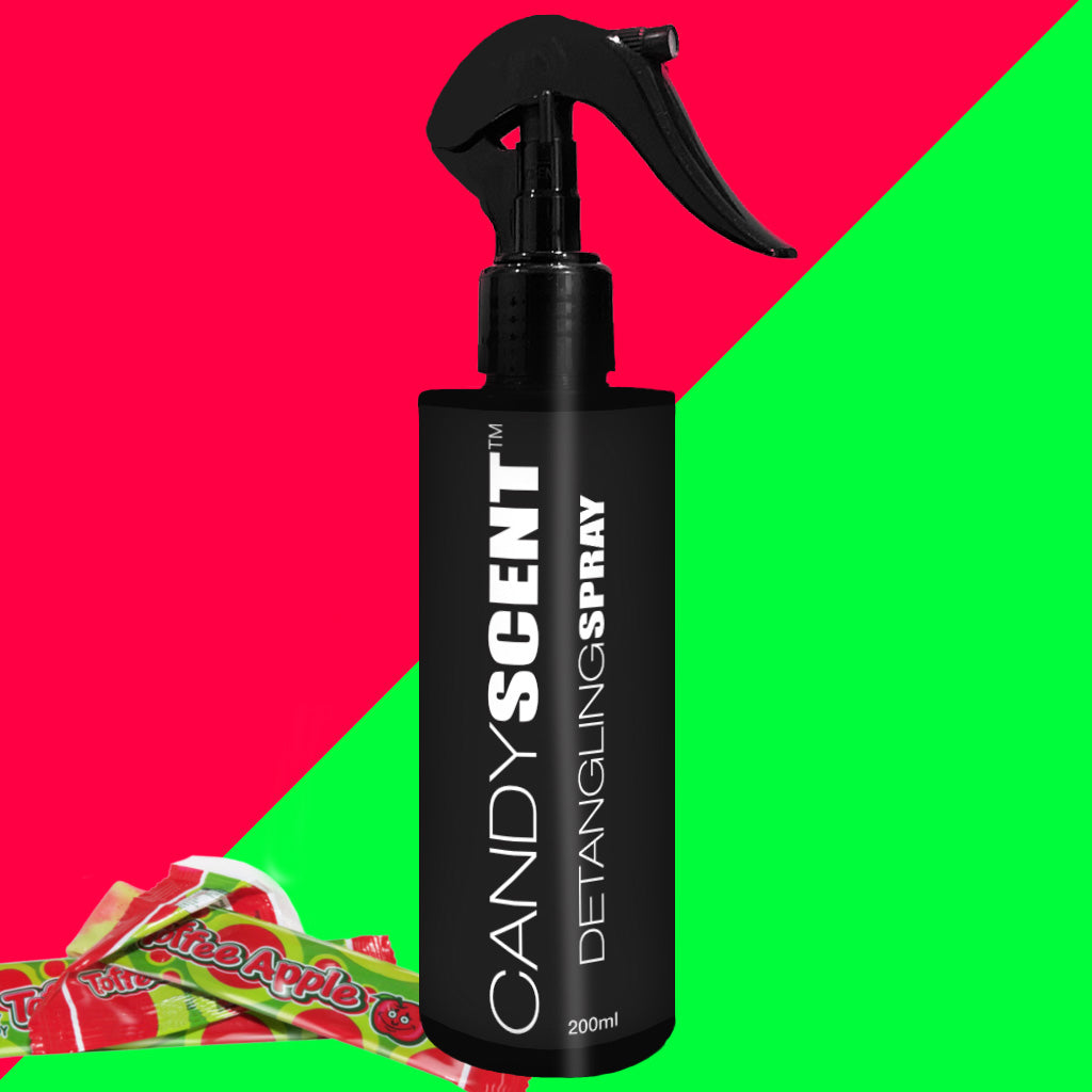 A black bottle of CANDYSCENT™ Hair Detangling Spray with a trigger spray nozzle is showcased against a split red and green backdrop. Infused with Aloe Vera, this 200ml bottle ensures smooth, tangle-free hair. Wrapped candies are scattered at the bottom left corner.