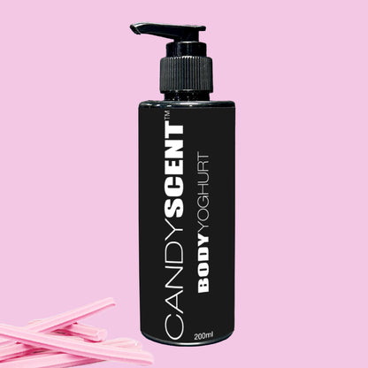 A black bottle of CANDYSCENT™ Body Yoghurt offers a nourishing experience with deep hydration. It is set against a pink background and marked with bold white text. Nearby, pink-striped sticks add a playful touch.