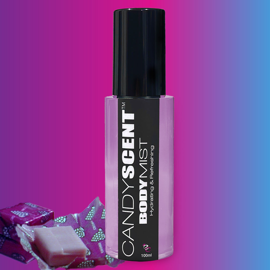 A bottle of CANDYSCENT™ Hydrating Body Mist is displayed against a gradient background transitioning from blue to pink. The pink bottle with a black cap reads "CANDYSCENT™ Hydrating Body Mist: Sweet and Refreshing." Two wrapped candies are placed beside it, hinting at the delightful fragrance within.