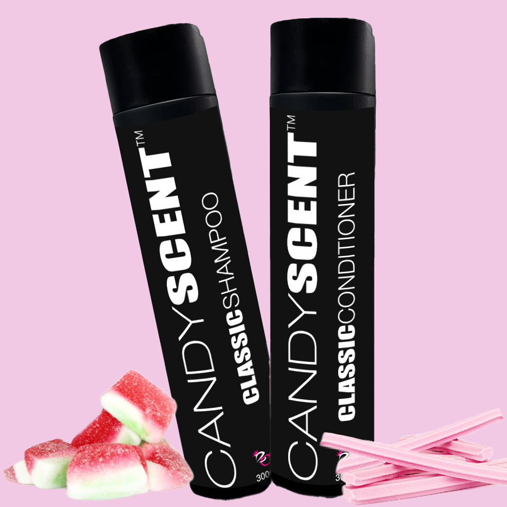 Two black bottles featuring the bold white "CANDYSCENT™" text—one labeled "Classic Shampoo" and the other labeled "Classic Conditioner." They are set against a pink background adorned with gummy candy and candy sticks at the bottom.