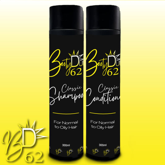 An image showing two black bottles of hair care products against a yellow background. The bottle on the left is labeled "BOOTY DUPE Classic Shampoo," and the one on the right is labeled "BOOTY DUPE Classic Conditioner." Both are part of the Classic Shampoo & Conditioner Bundle targeting normal to oily hair, promising smooth, shiny, healthy locks in 300 ml.